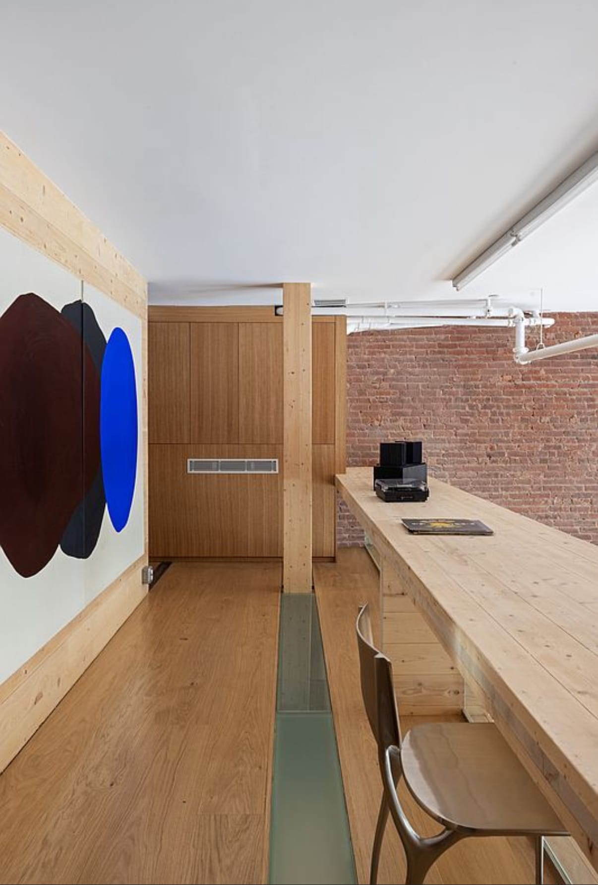 Built-in wood desk and shelving against an exposed brick wall