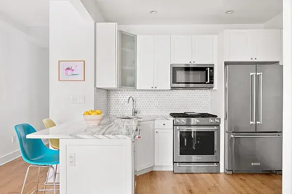 Compact white kitchen with marble island and colorful modern seating