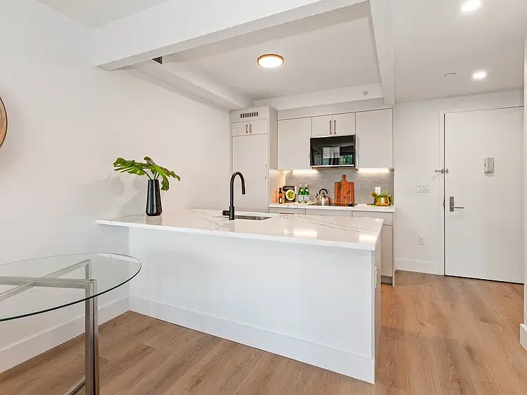 Contemporary white kitchen with marble waterfall island and glass table