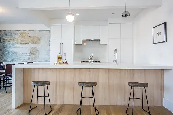 Contemporary white kitchen with natural wood island and bar stool seating