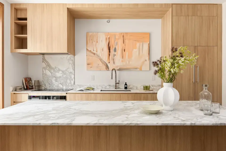 Close-up view of completed kitchen showing wood cabinetry detail and marble island