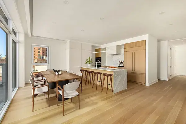 Modern kitchen and dining area with wood cabinetry, marble island, and floor-to-ceiling windows