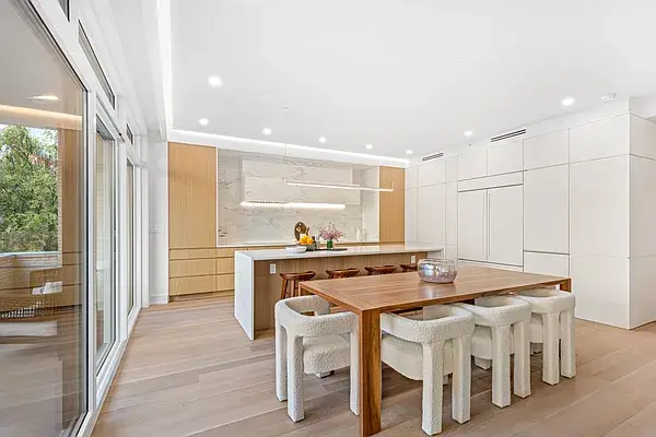 Completed contemporary kitchen with wood and white cabinets, island dining area, and terrace access