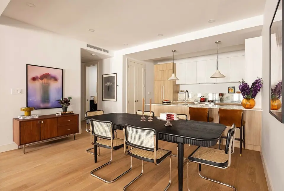 Dining room with a white and light wood kitchen and pendant lights behind