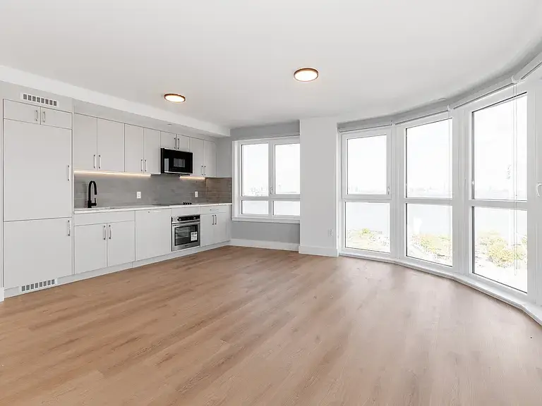 Minimalist white kitchen with wood floors and bay windows