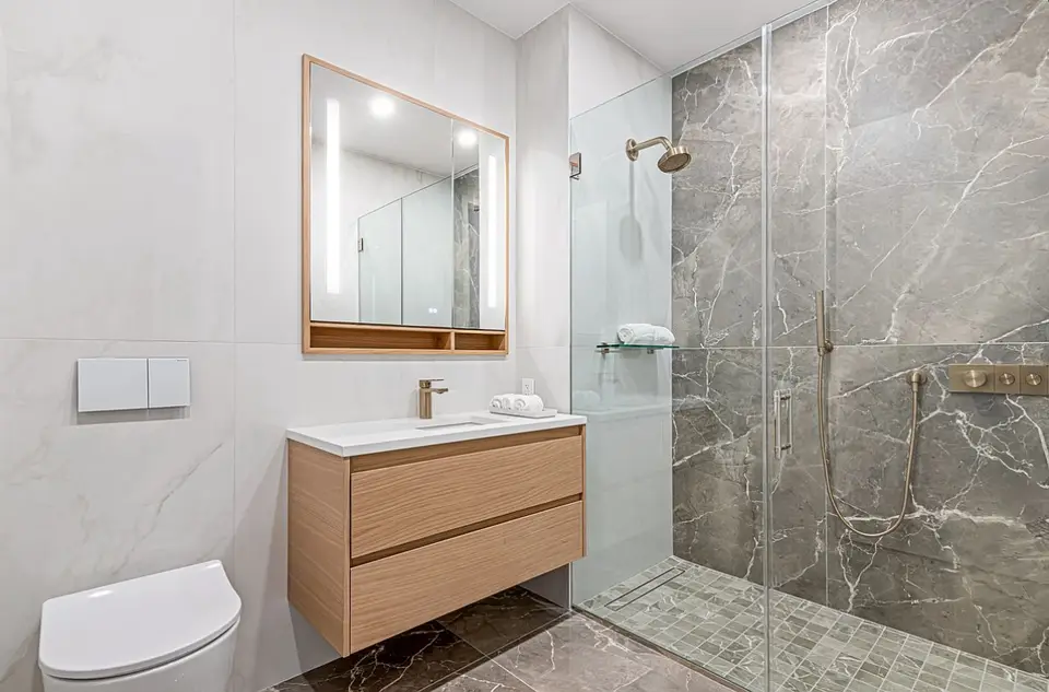 Modern bathroom with floating wood vanity and marble walk-in shower