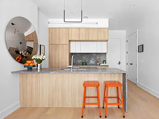 Modern kitchen with wood island, gray marble countertop, and orange bar stools