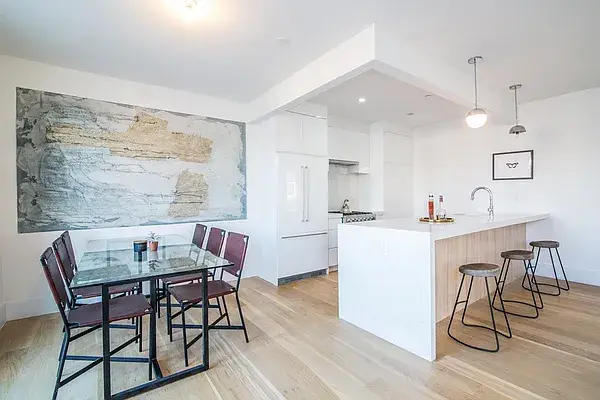 Modern white kitchen with wood island and open concept dining area
