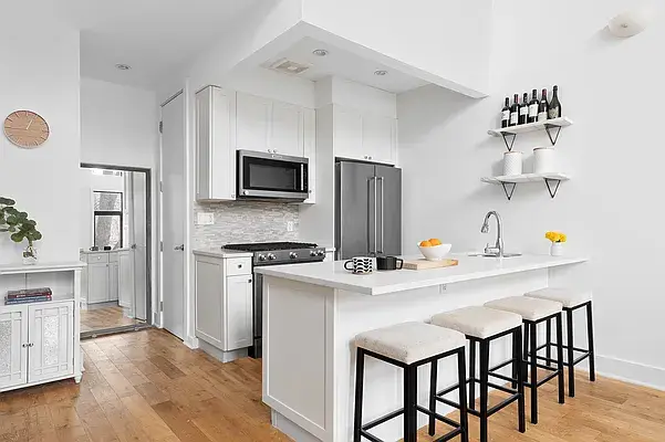 Modern white kitchen with island, marble countertops, and bar stool seating