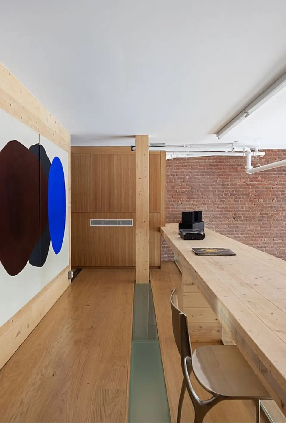 Modern workspace with natural wood desk and exposed brick wall