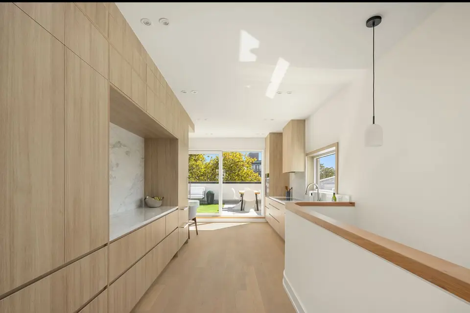 Natural wood galley kitchen with marble backsplash and white countertops
