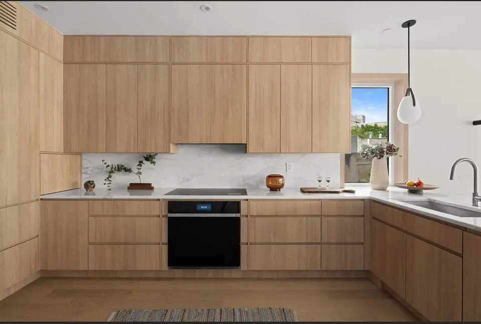 Natural wood kitchen with marble backsplash and countertops