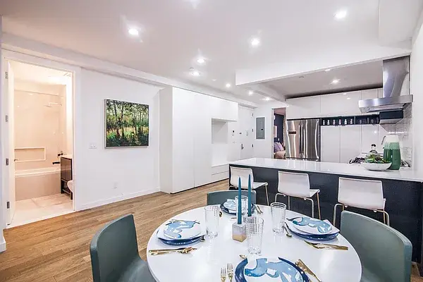 Open concept white kitchen with black island and dining area