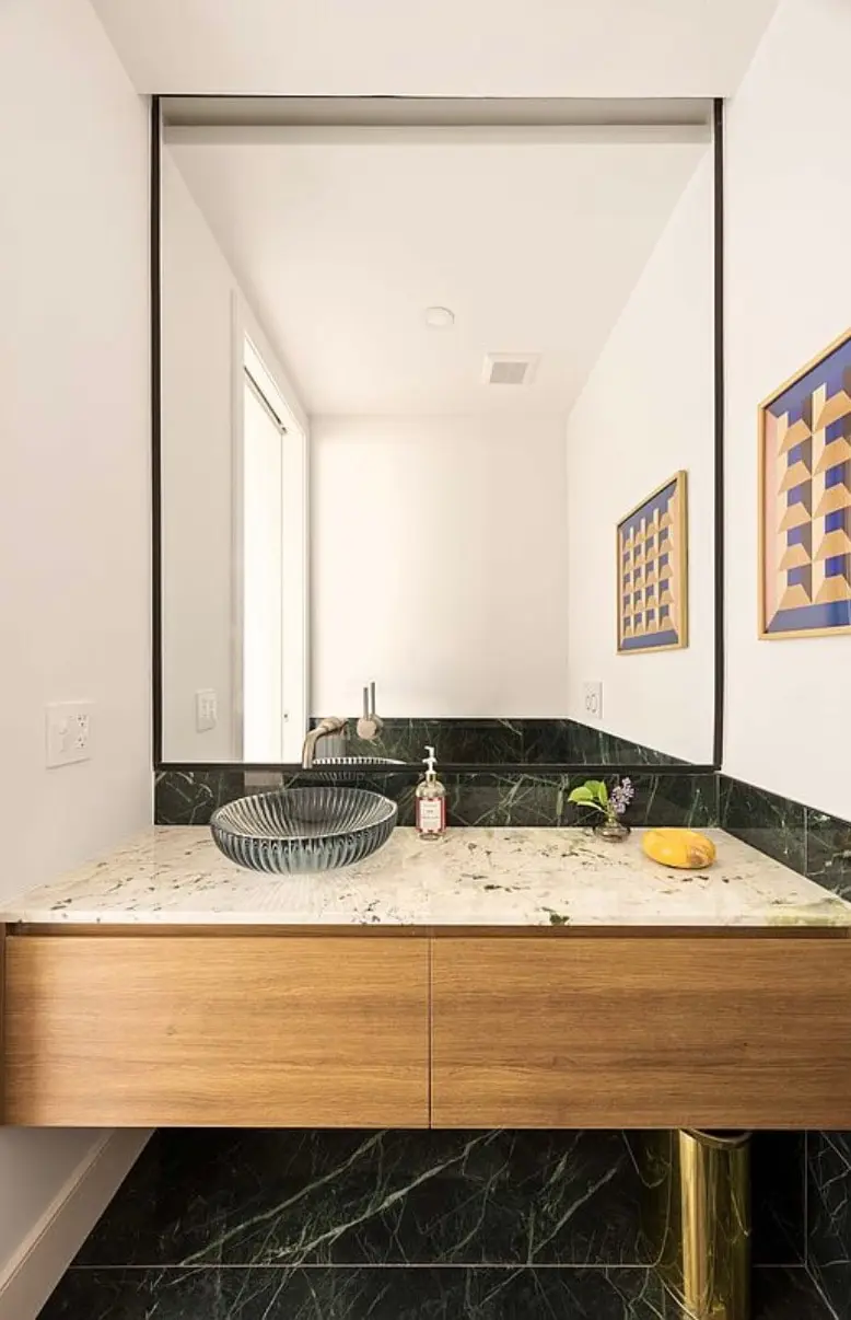 Powder room with floating wood vanity, stone top, glass vessel sink, and green marble