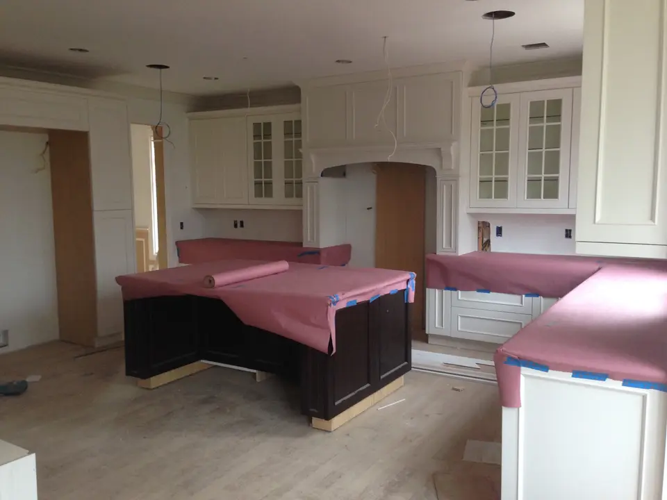 White kitchen construction with dark wood island in progress