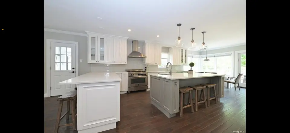 White kitchen with gray island and wood bar stool seating