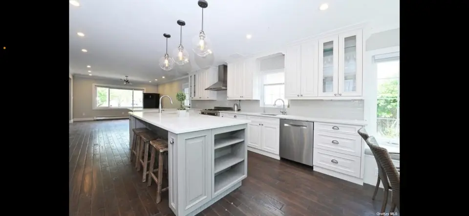 White kitchen island featuring open shelving and glass pendants
