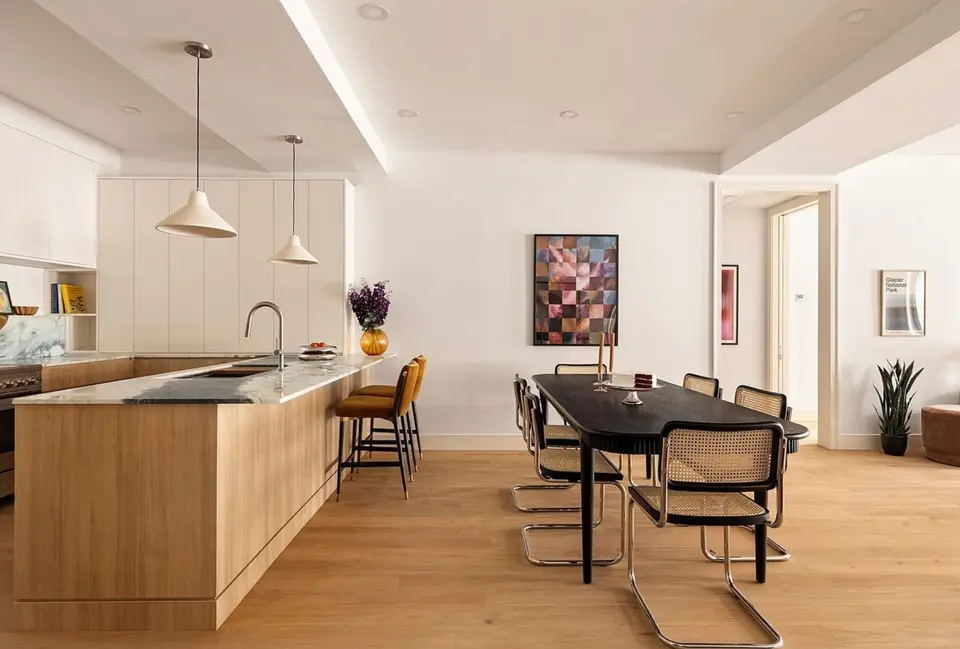 Light wood kitchen peninsula with bar seating beside the dining room