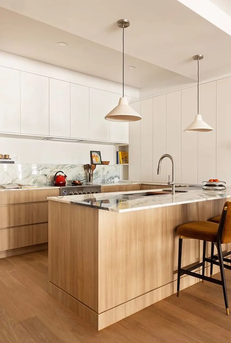 Light wood peninsula with marble top in front of white floor-to-ceiling cabinets